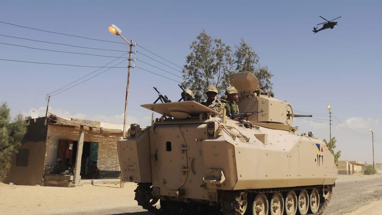 Egyptian Army soldiers patrol in an armored vehicle backed by a helicopter gunship during a sweep through villages in Sheikh Zuweyid, north Sinai