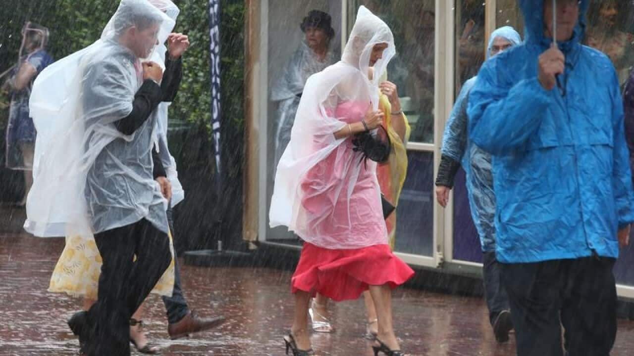 Racegoers get caught in heavy rain at the Melbourne Cup.
