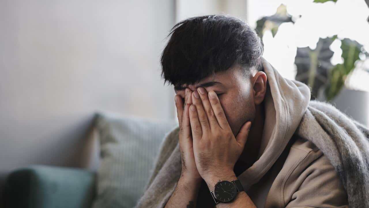Ill man on sofa with hands covering face