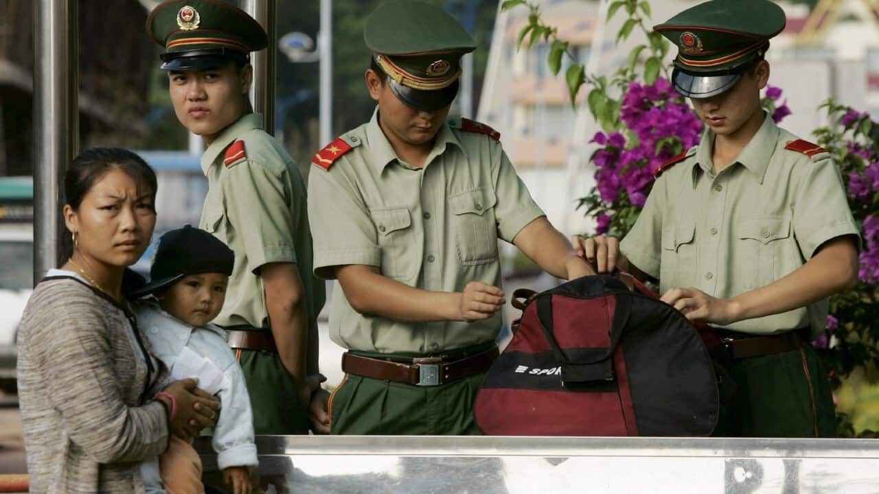 Chinese paramilitary police inspect the luggage of a woman entering China on the Laos border, at the Mohan Land Port in Xishuangbanna Dai Autonomous Prefecture (AAP Image - EPAMICHAEL REYNOLDS)