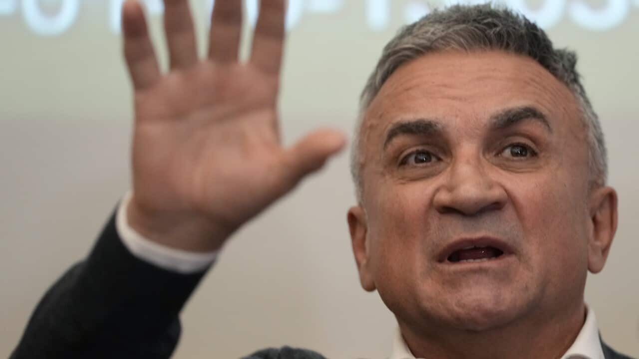 A man speaking while his hand is raised.