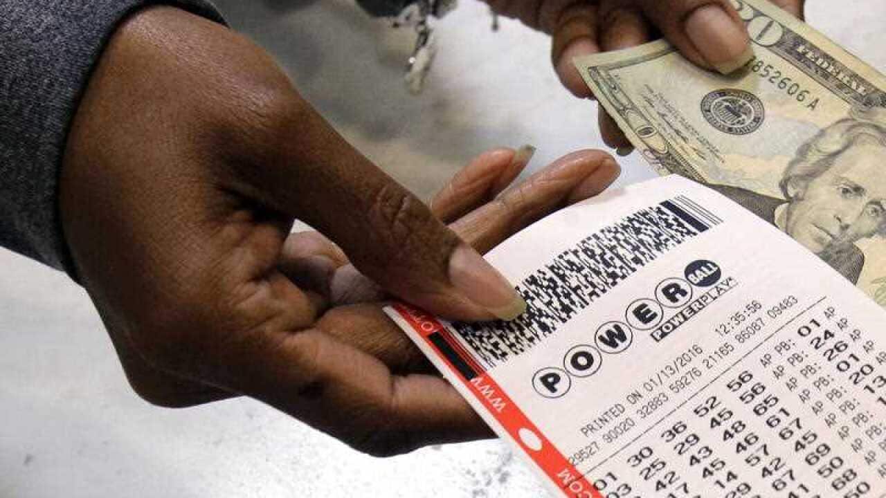 A clerk hands over a Powerball ticket for cash at Tower City Lottery Stop.