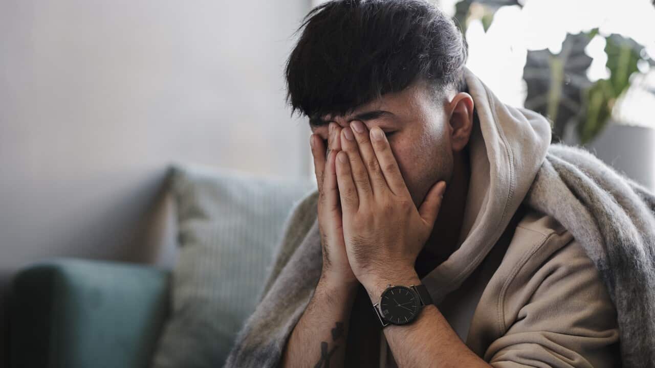 Ill man on sofa with hands covering face