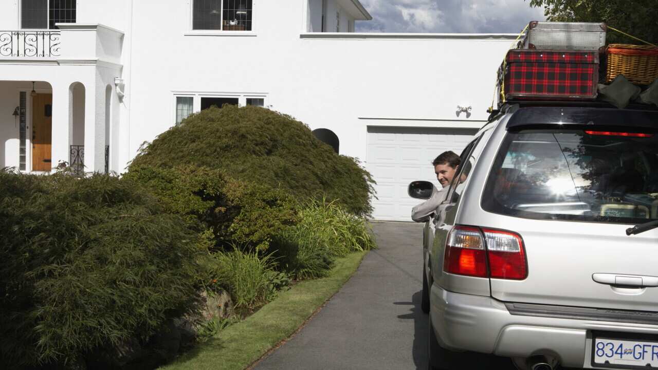 Man looking out of window of car on front drive, smiling