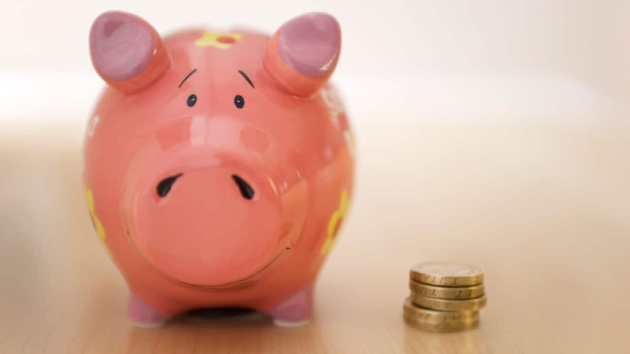 Stack of gold coins standing next to piggy bank