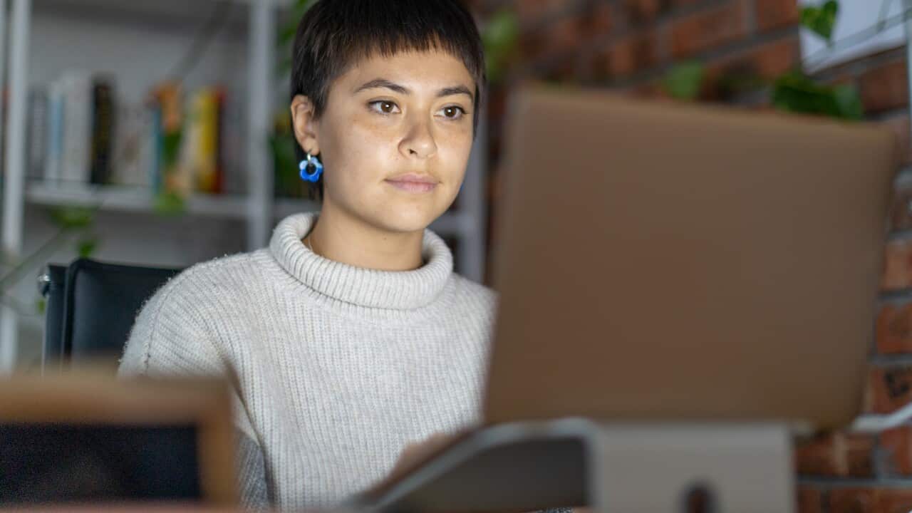 A woman sitting at her desk in front of her laptop.