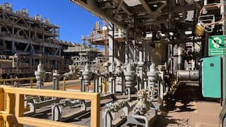 A photo of the Barrow Island natural gas plant in Western Australia. It is a maze of silver pipework against a bright blue sky.