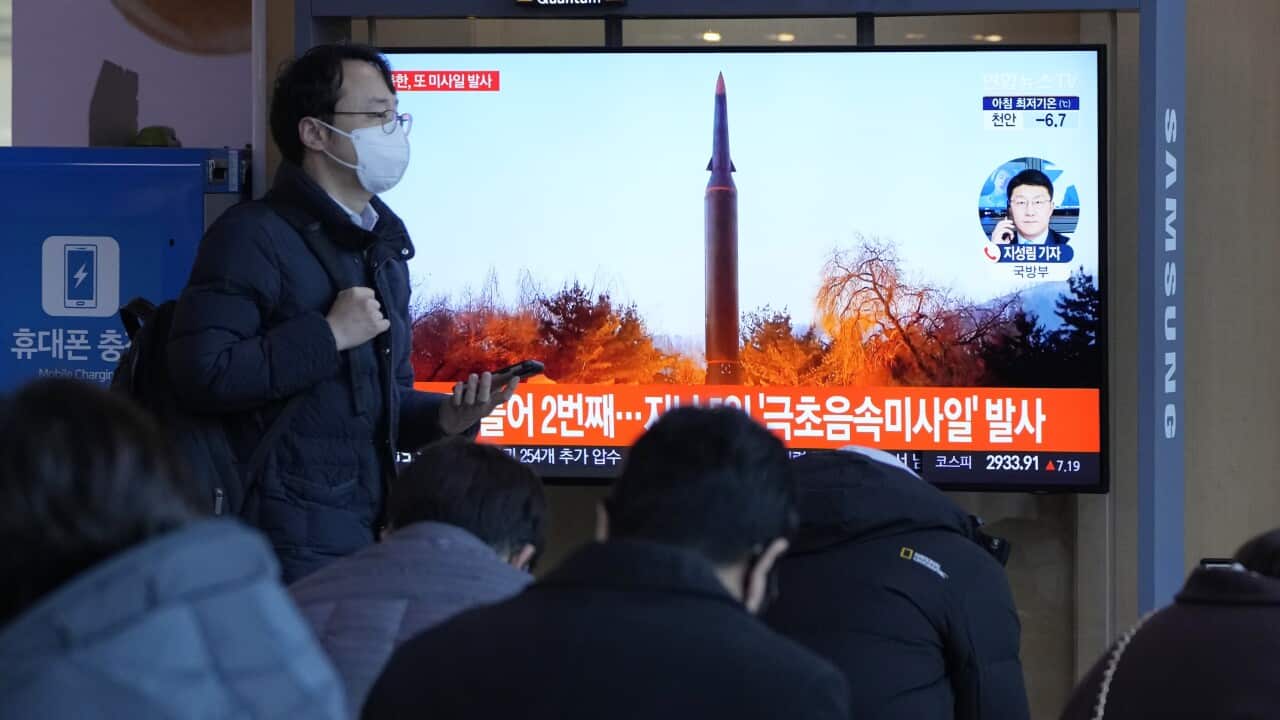 People watch a TV showing a file image of North Korea's missile launch