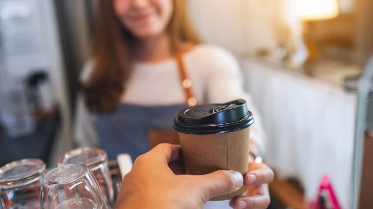 Closeup image of a waitress holding and serving paper cups of ho