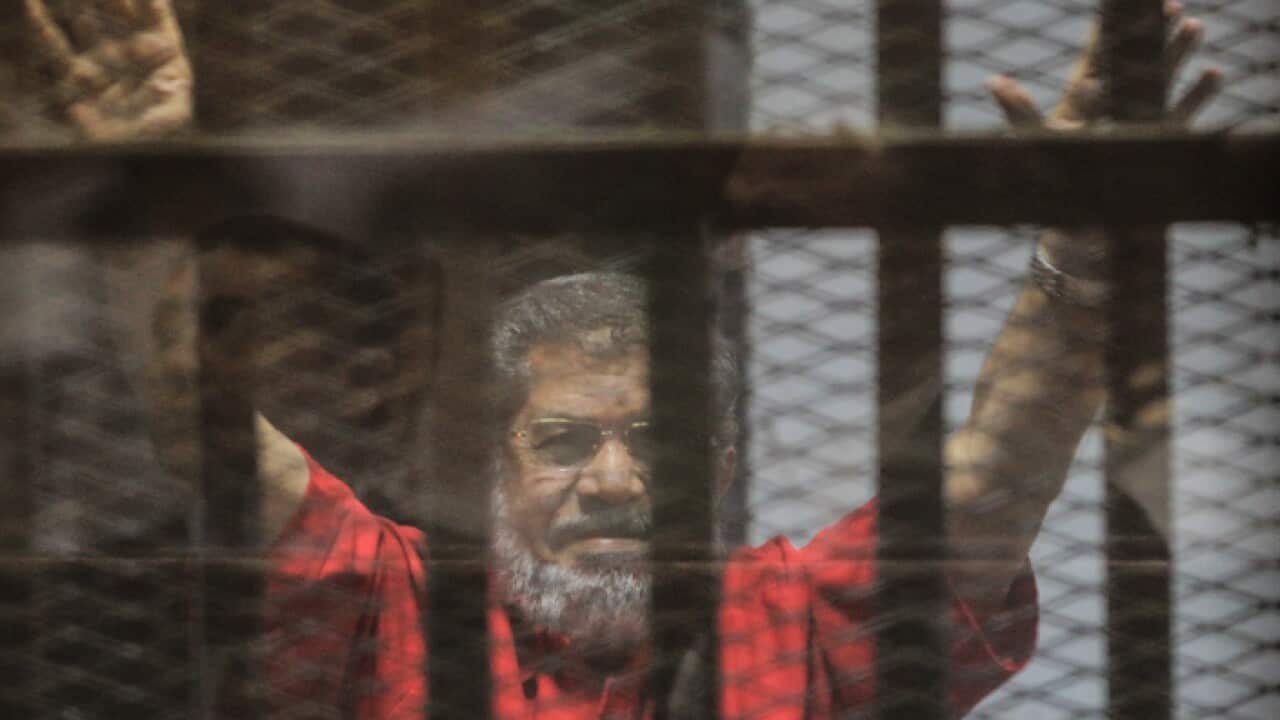 Mohamed Morsi gestures during a trial session on charges of espionage in Cairo, Egypt