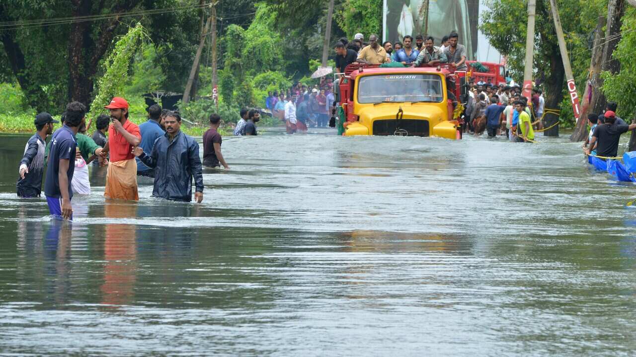 A truck carries people past a flooded road in Thrissur, in the southern Indian state of Kerala.