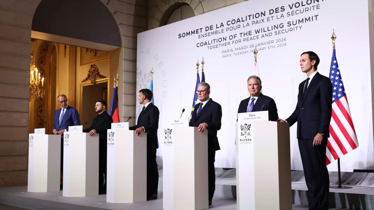 World leaders, including Volodymyr Zelenskyy and Emmanuel Macron, stand at a row of white podiums.