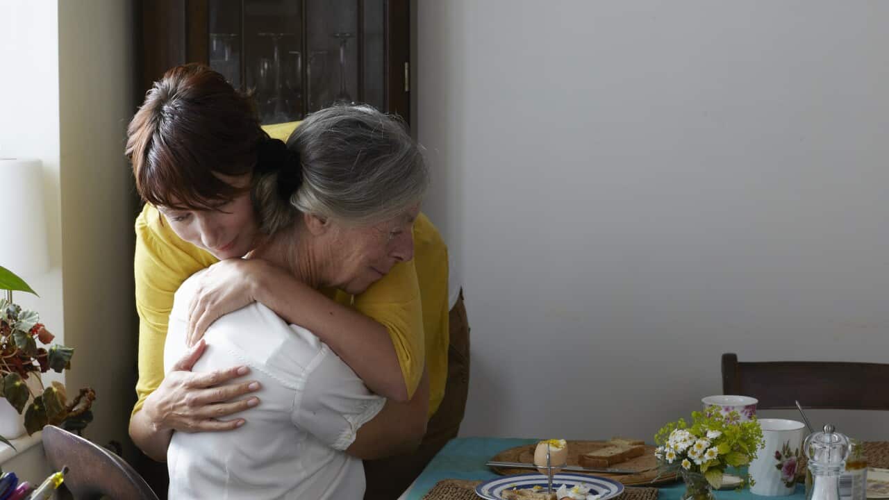 Daughter embracing elderly mother in her home