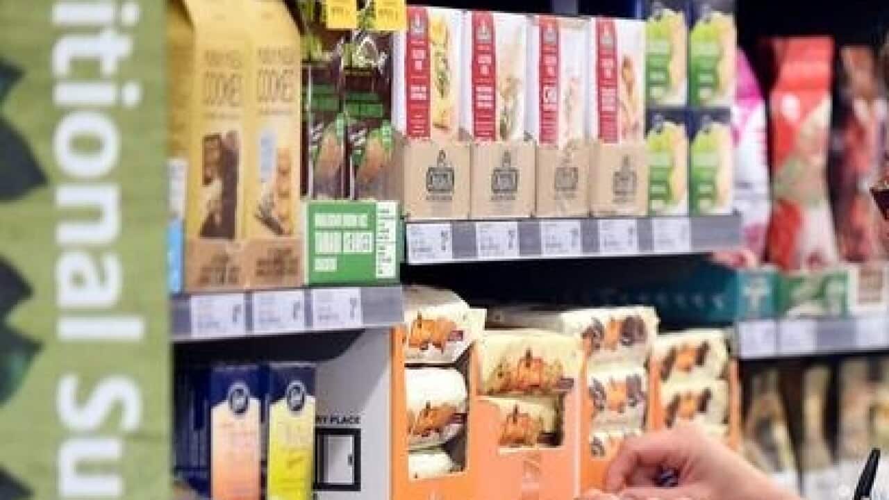 An employee puts price tags on selves at a Woolworths supermarket