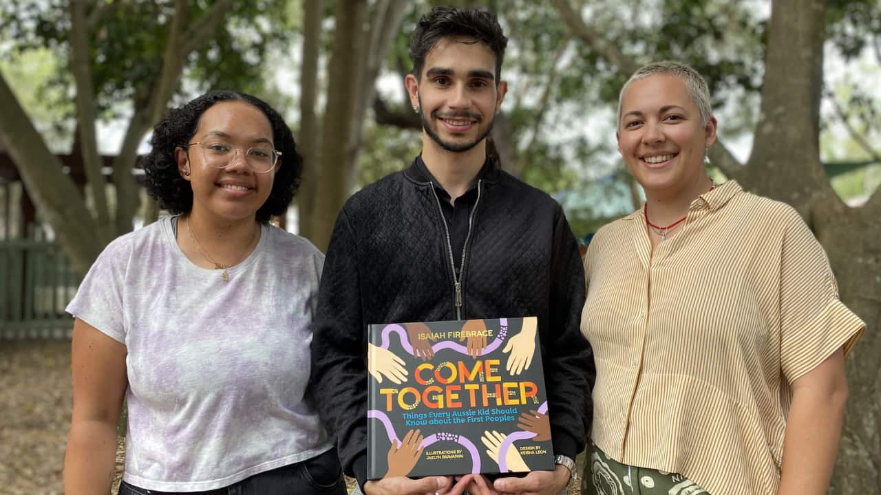 Isaiah Firebrace (middle) celebrates with illustrator Jaelyn Biumaiwai and designer Keisha Leon at the book launch at Dreamworld on the Gold Coast.