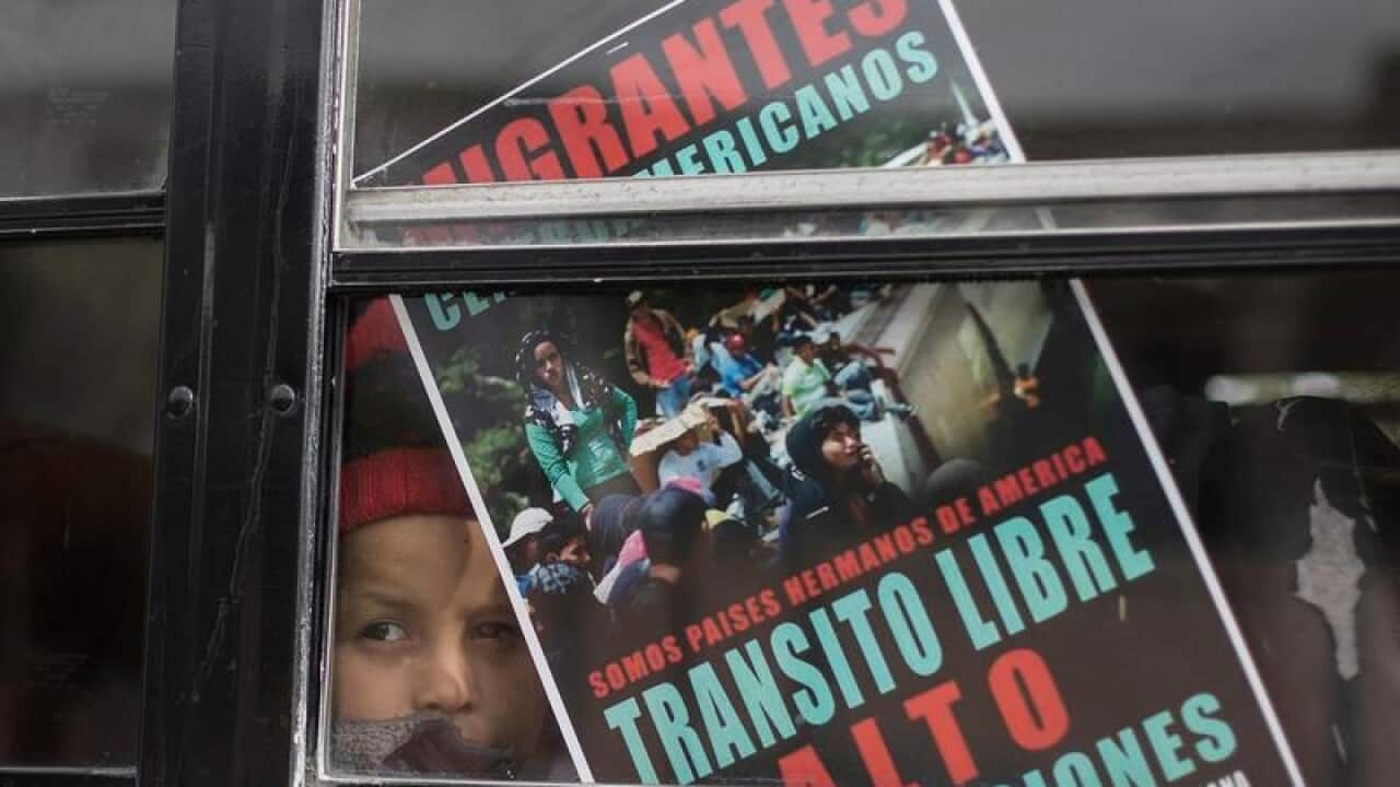 A Central American child peers out of a bus window