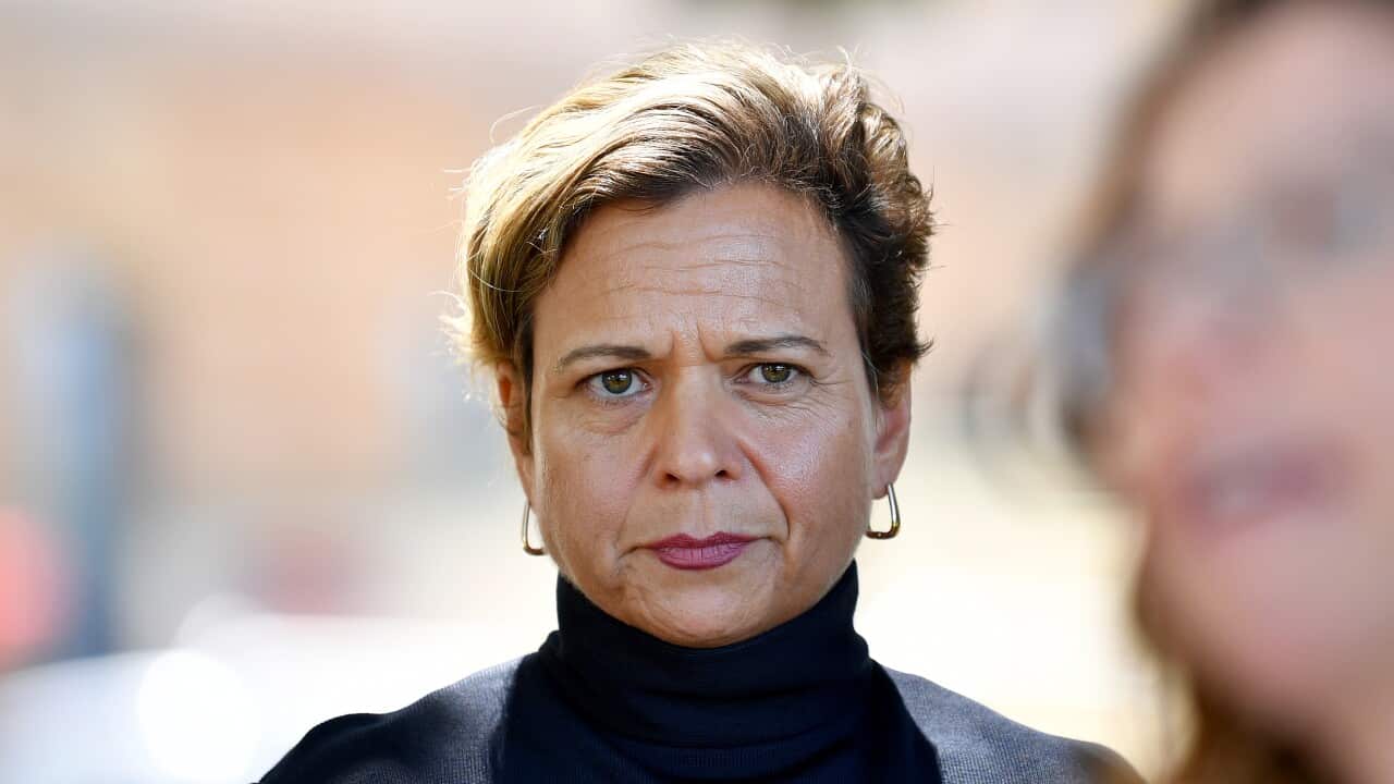 MICHELLE ROWLAND standing in a black top.