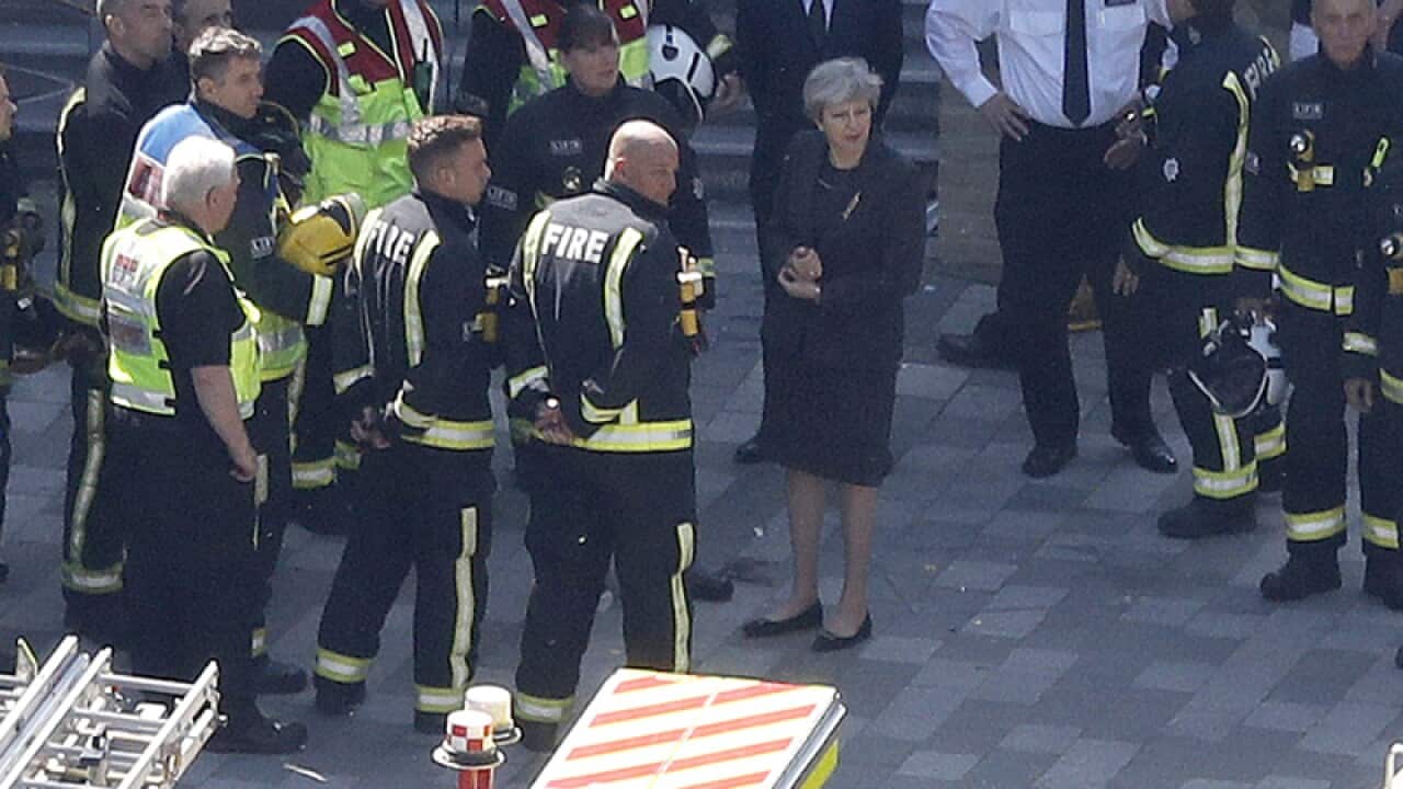 PM Theresa May, center, arrives at Grenfield Tower in London