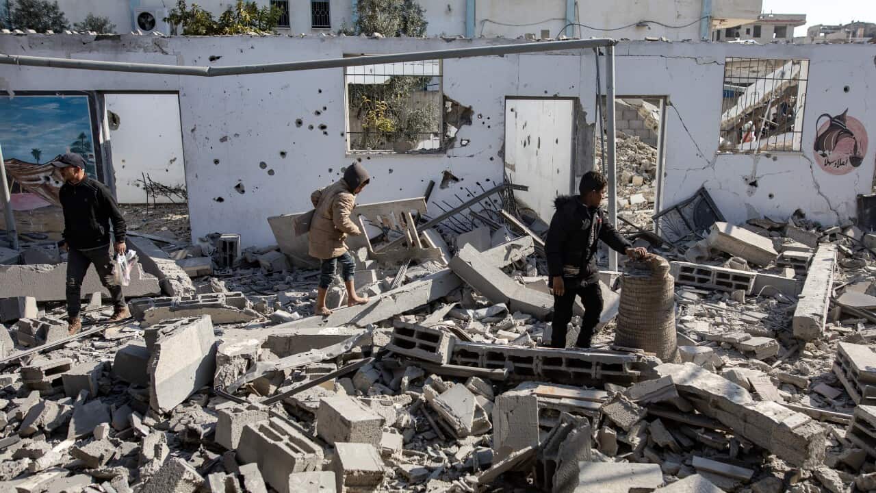 People walking through the rubble of a destroyed building.