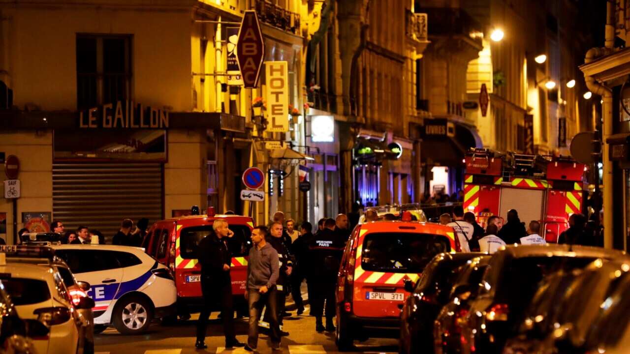 Policemen and emergency service members stand in a blocked street in Paris centre after one person was killed and several injured