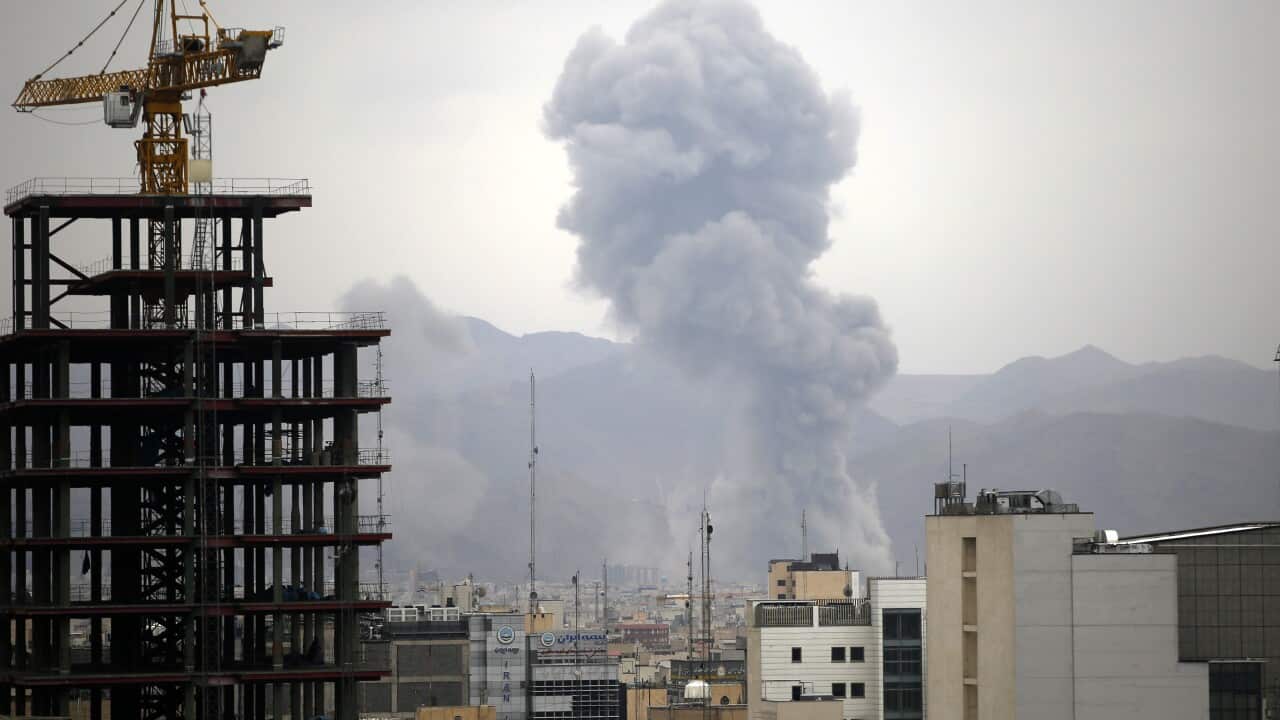 A cloud of smoke rising above buildings.