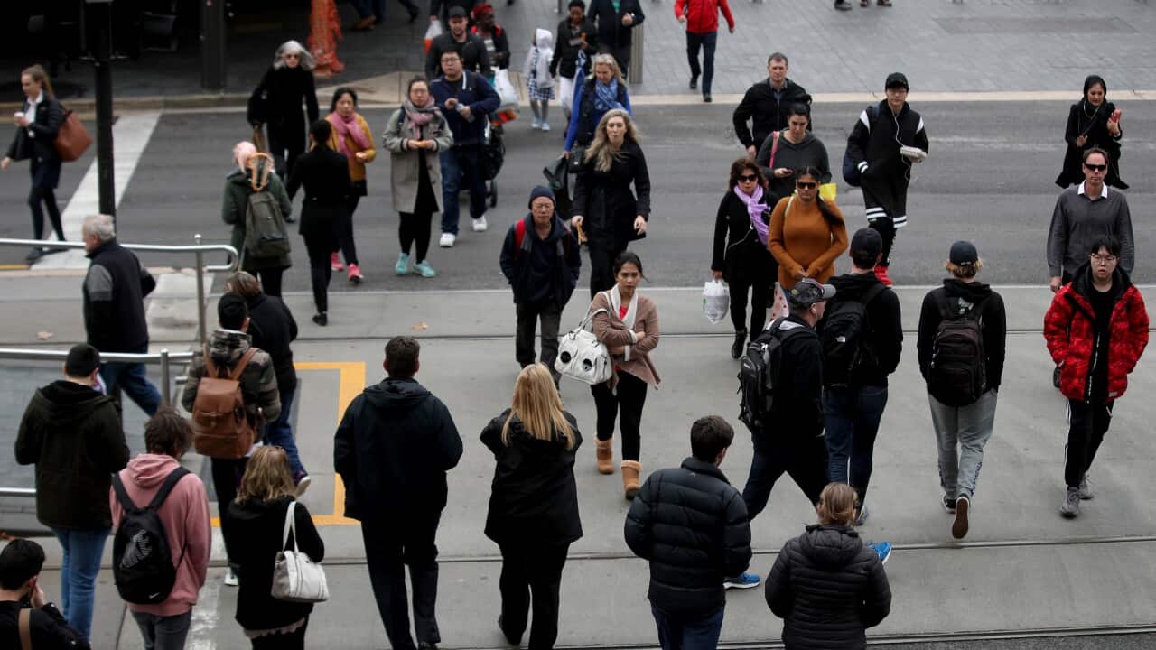 A big crowd of people walking across a large road.