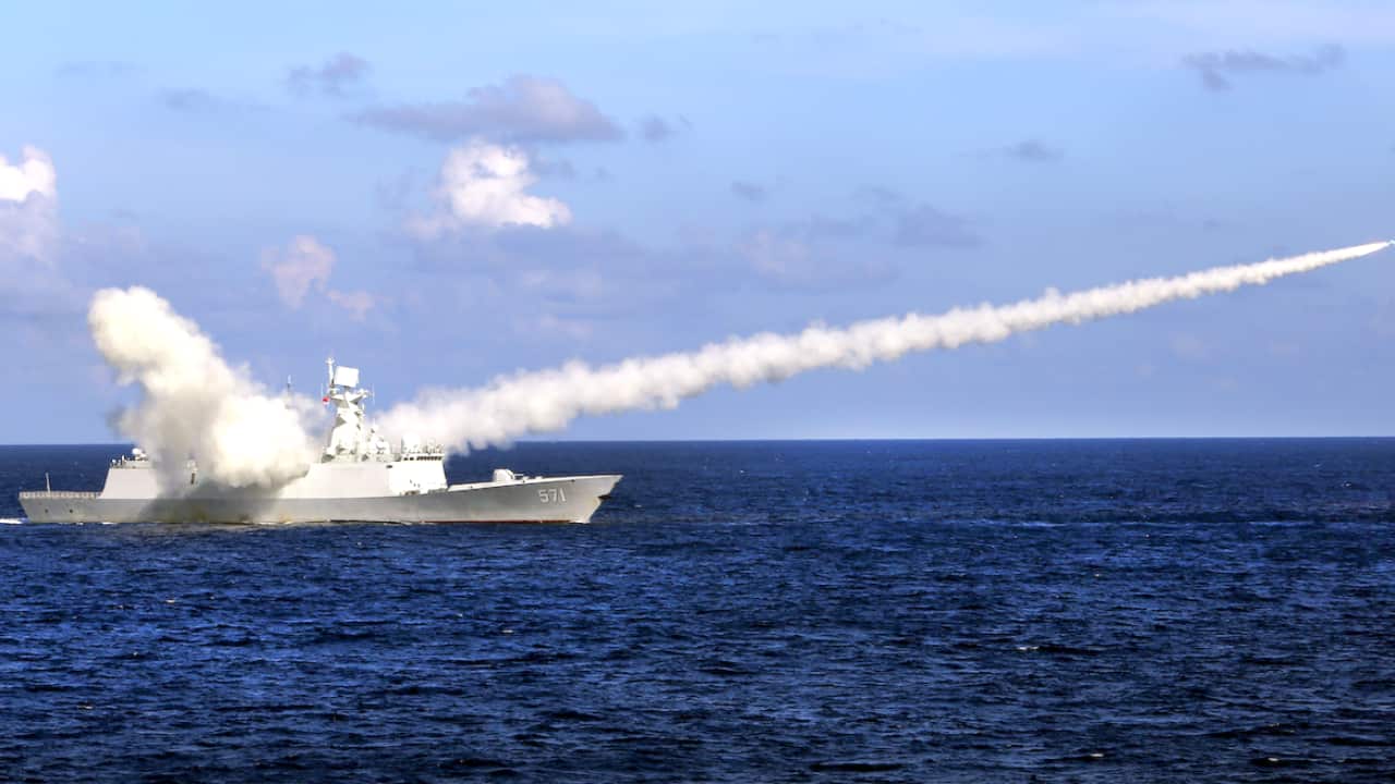 A chinese ship fires a missile leaving a trail of smoke.