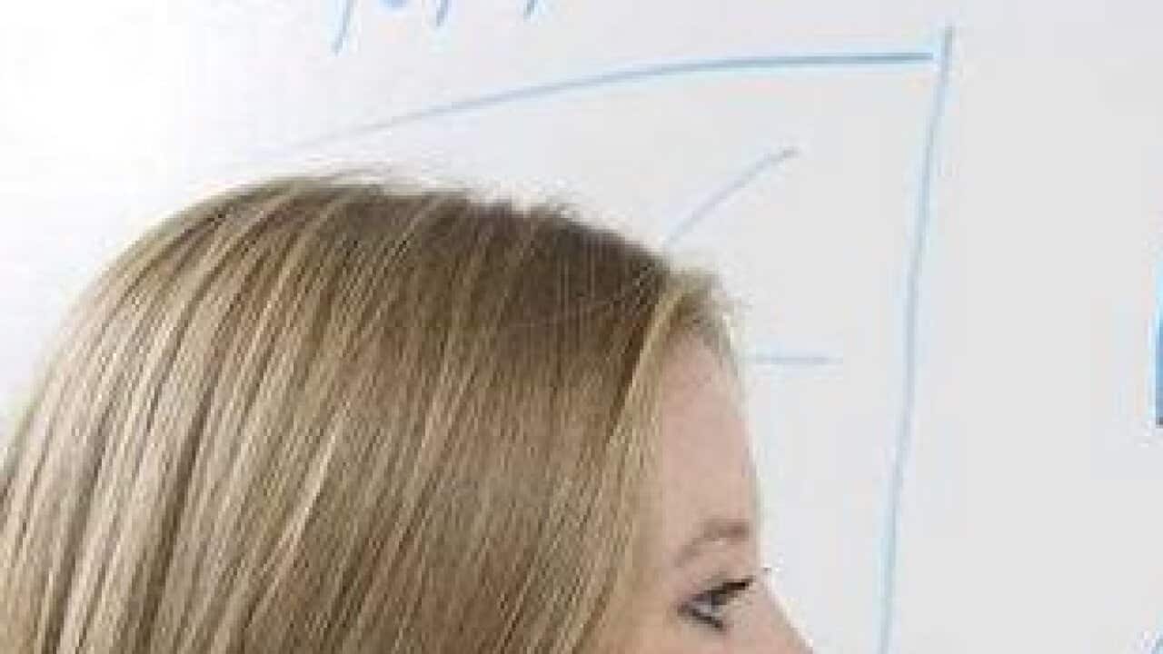 Female student writing maths equations on whiteboard