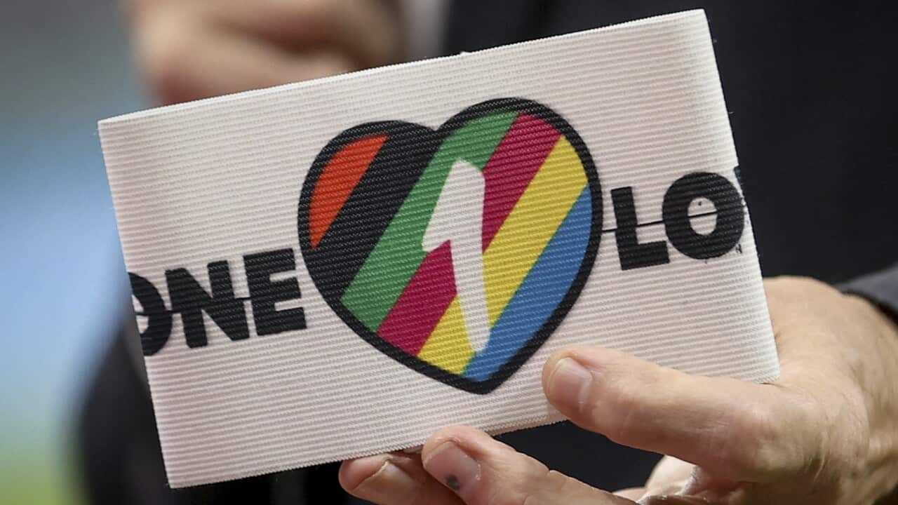 A hand holds up a OneLove armband