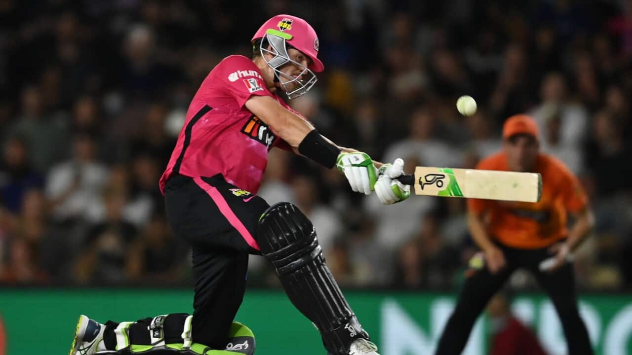 A member of the Sydney Sixers cricket swinging his bat at the ball.