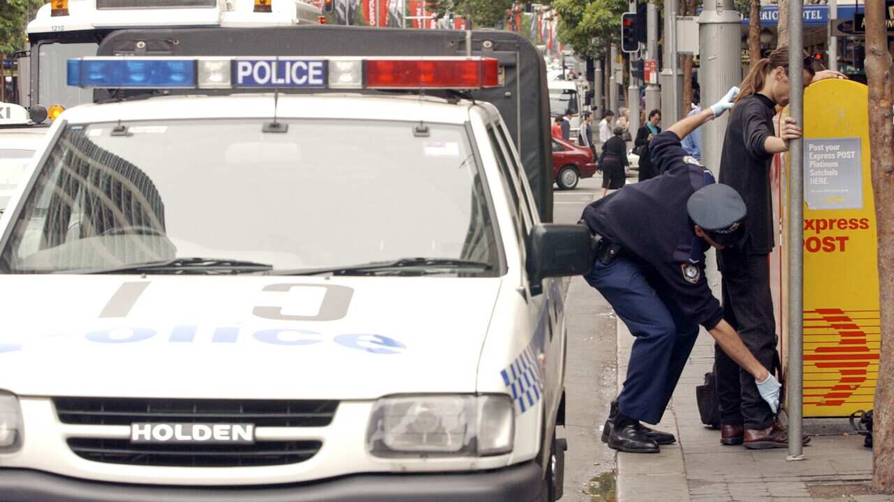 Sydney, November 21, 2002. NSW Police officers search a member of the public in Sydney's CBD as police and security personel are becoming more vigilant after the announcement of Australia heightened terrorism alert. (AAP Image/Dean Lewins) NO ARCHIVING