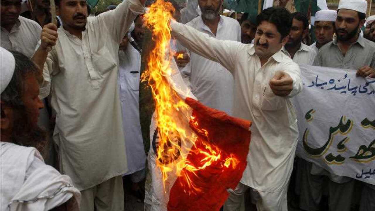 Pakistani protesters burn a representation of an Indian flag in Peshawar, Pakistan, to condemn the killings of Pakistani soldiers