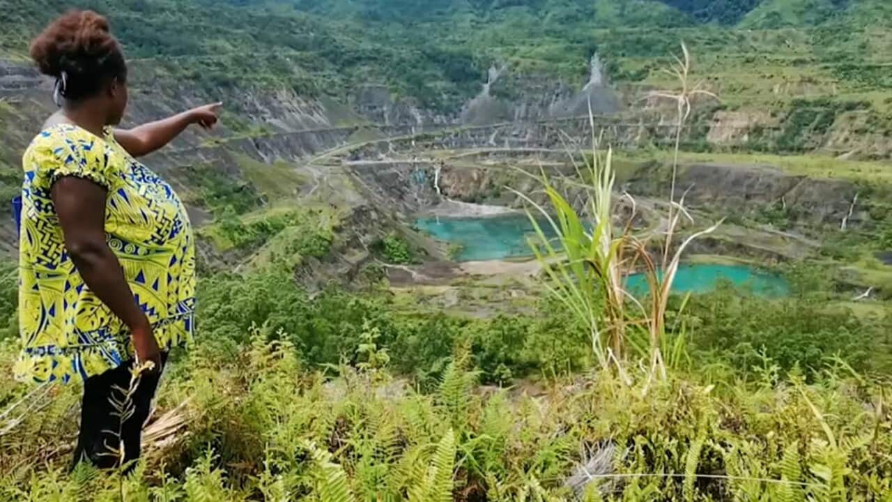 Bougainville local woman pointing at what's left of the Panguna mine.