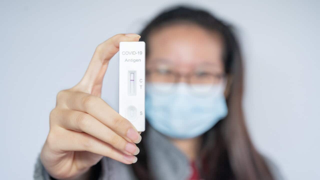Asian woman holding a rapid antigen test pad after testing result is negative.