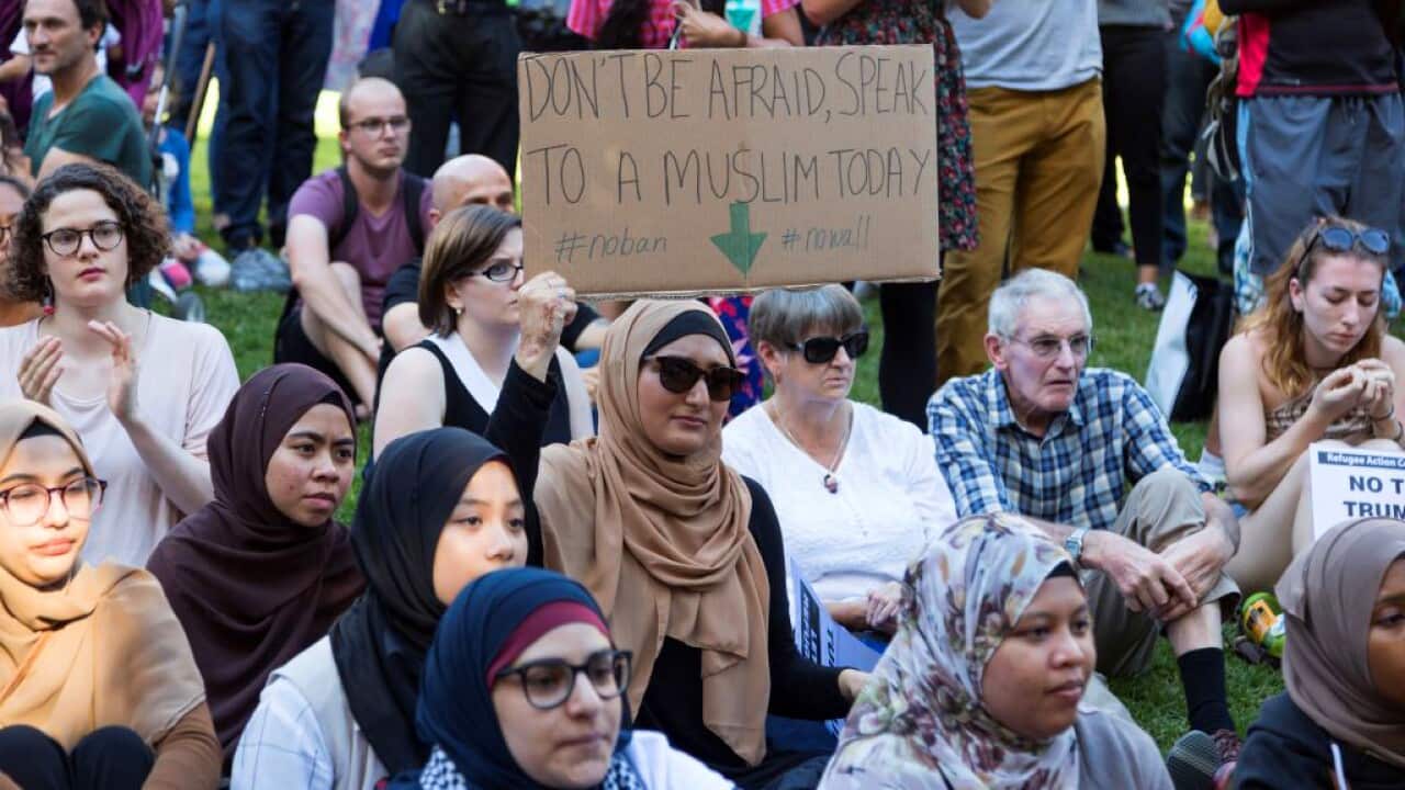 A Muslim woman hold a placard reading 'Don't be afraid to speak to a Muslim today' during a recent protest against US President Donald Trump in Melbourne.