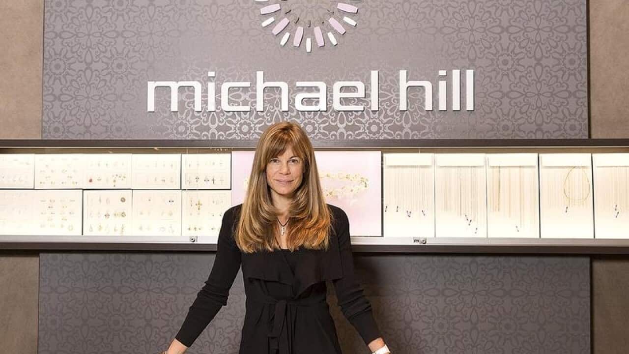 Michael Hill chair Emma Hill behind counter with signage behind her