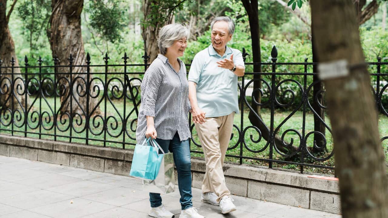 Smiling,affectionate senior couple walking on urban sidewalk