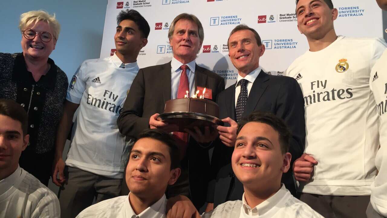 Vice Chancellor Torrens University Justin Beilby (centre left) holds a cake with Real Madrid Legend Emiliano Butraguen (centre right).