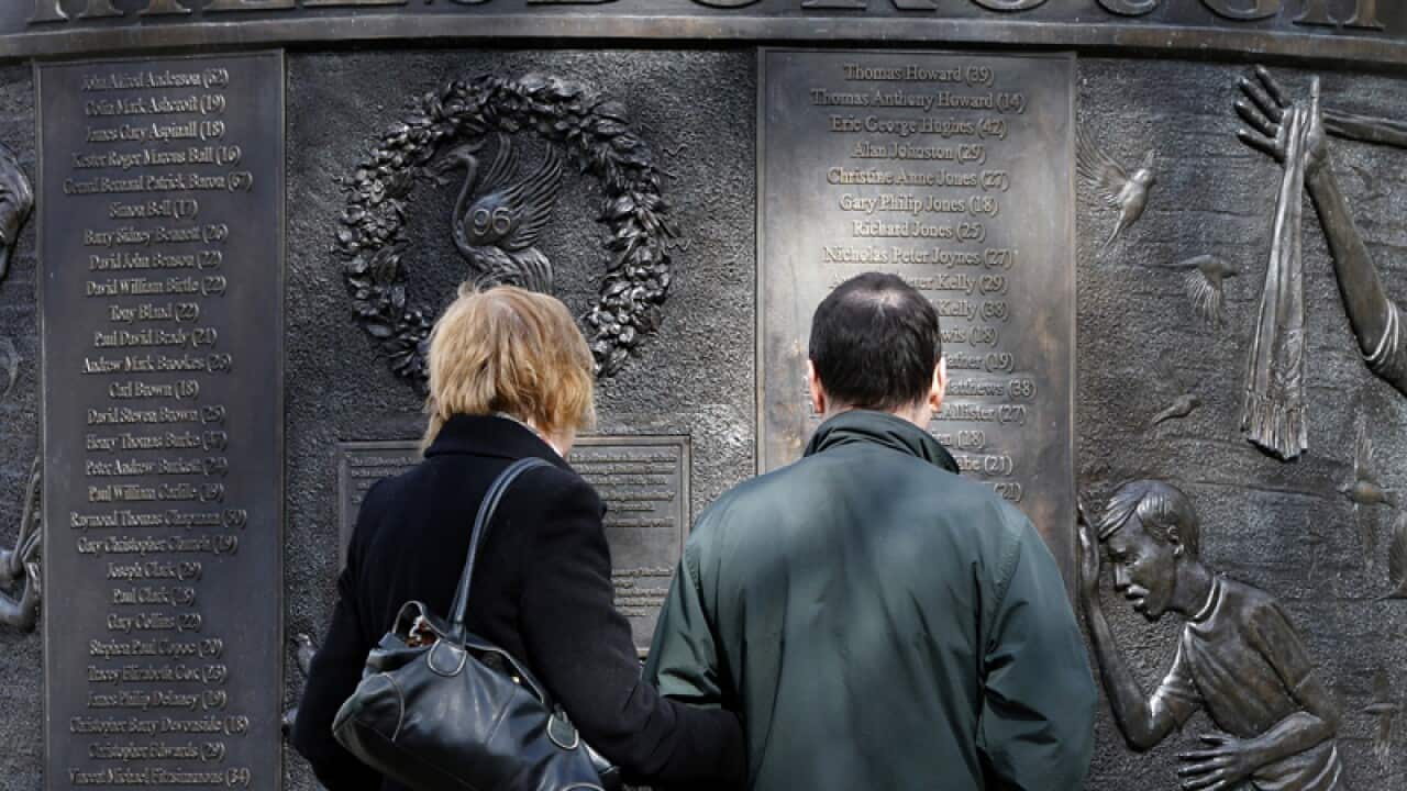 People look at a sculpture in memory of the Hillsborough Disaster