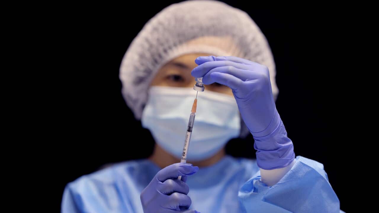 A health care worker fills a syringe with the Pfizer vaccine.