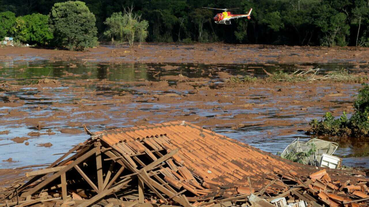Rescue workers in a helicopter search a flooded area after a dam collapsed in Brumadinho, Brazil