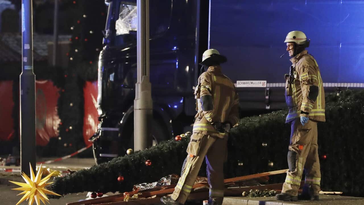 Firefighters look at a toppled Christmas tree after a truck ran into a crowded Christmas market and killed several people in Berlin, Germany