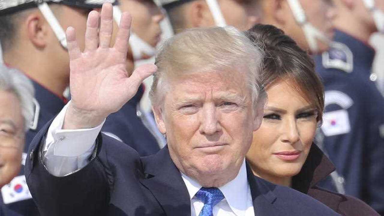 U.S. President Donald Trump waves as first lady Melania Trump, center right, stands upon their arrival at Osan Air Base in Pyeongtaek, South Korea, Tuesday, Nov. 7, 2017.