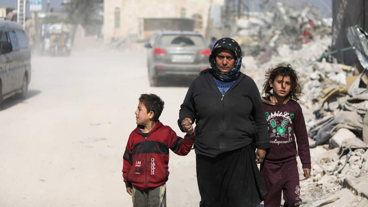 A woman holding the hands of two children