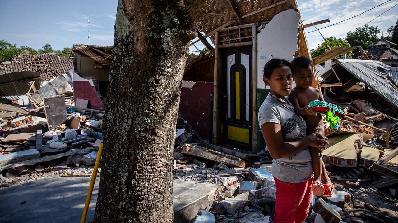 A mother and son stand near the ruins of their home following an earthquake in Pemenang on August 8, 2018 in Lombok.