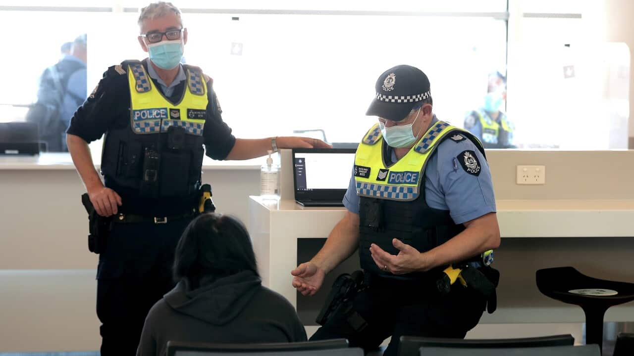 Police talk to a passenger at Perth Airport - WA borders stay closed until next year