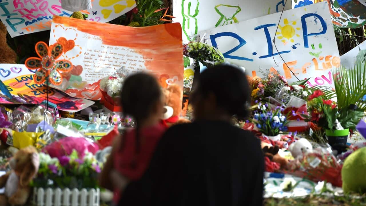Mourners attend a floral tribute near a house in which eight children killed in the Cairns suburb of Manoora, Sunday, Dec. 21, 2014.