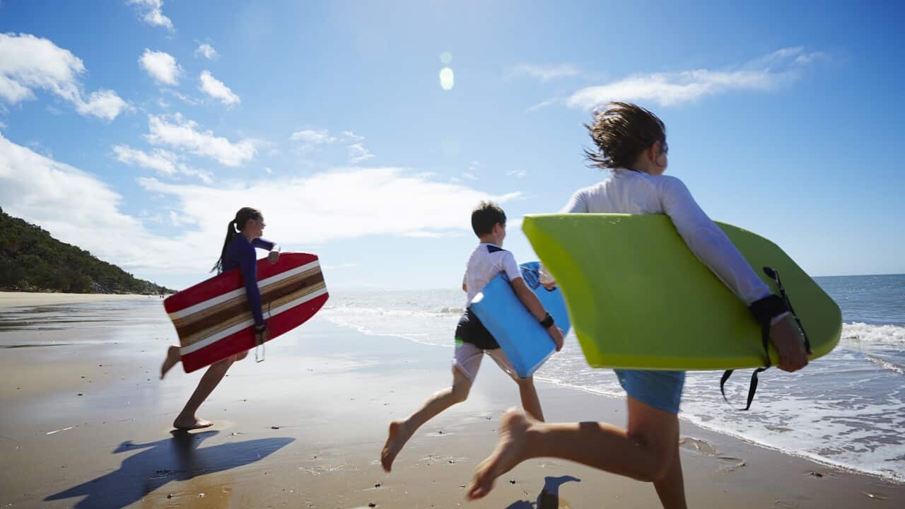 Three children running into the ocean
