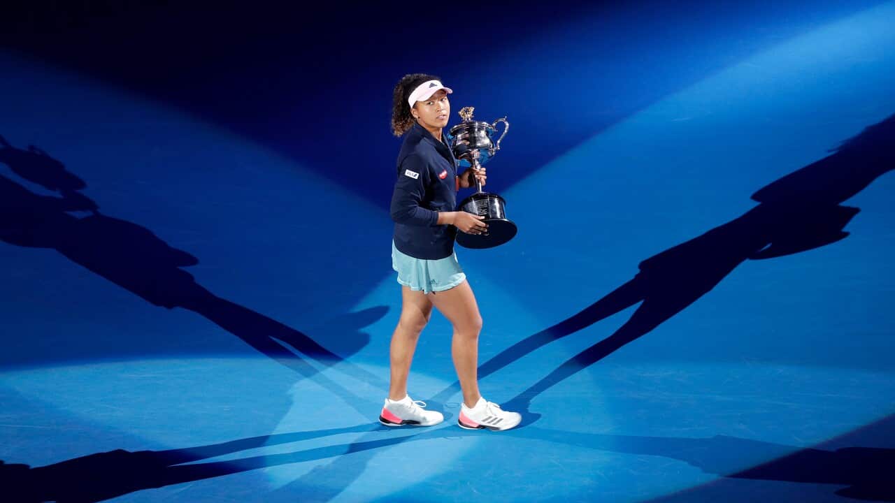 Japans Naomi Osaka walks around Rod Laver Arena with her trophy after defeating Petra Kvitova of the Czech Republic at the Australian Open tennis championships.