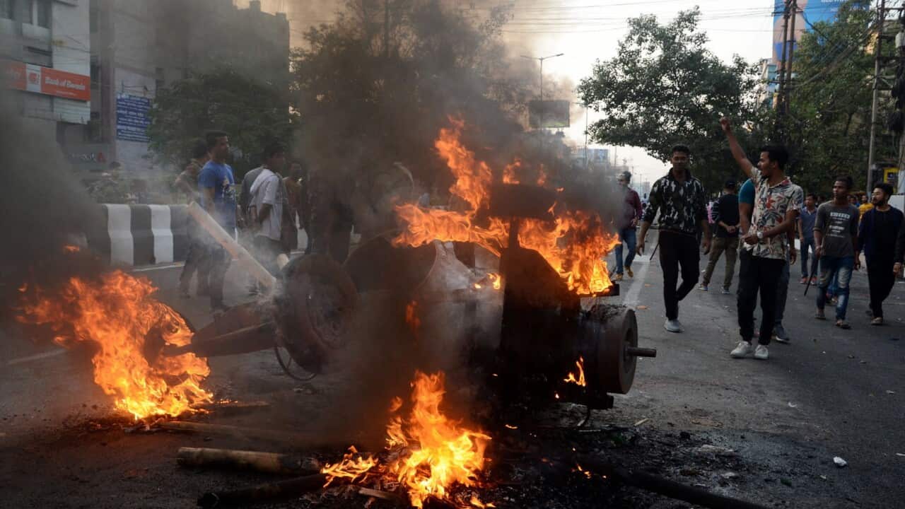 A burning trailer sits on a road during protests against the Citizenship Amendment Bill in Guwahati, Assam, India.